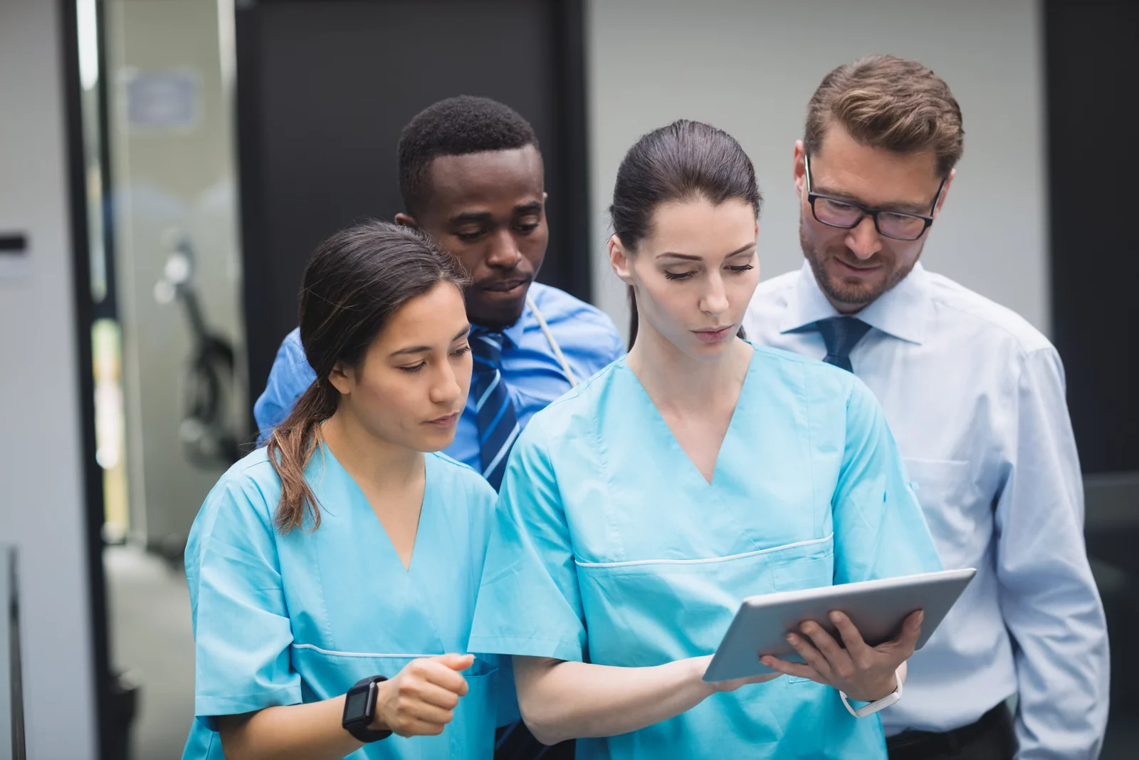 Nursing students in scrubs reviewing a tablet with an instructor