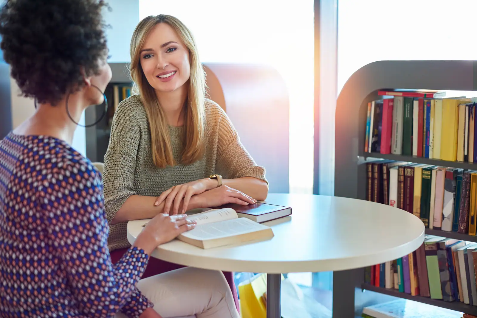 Student talking through a course plan with an adviser at a library table
