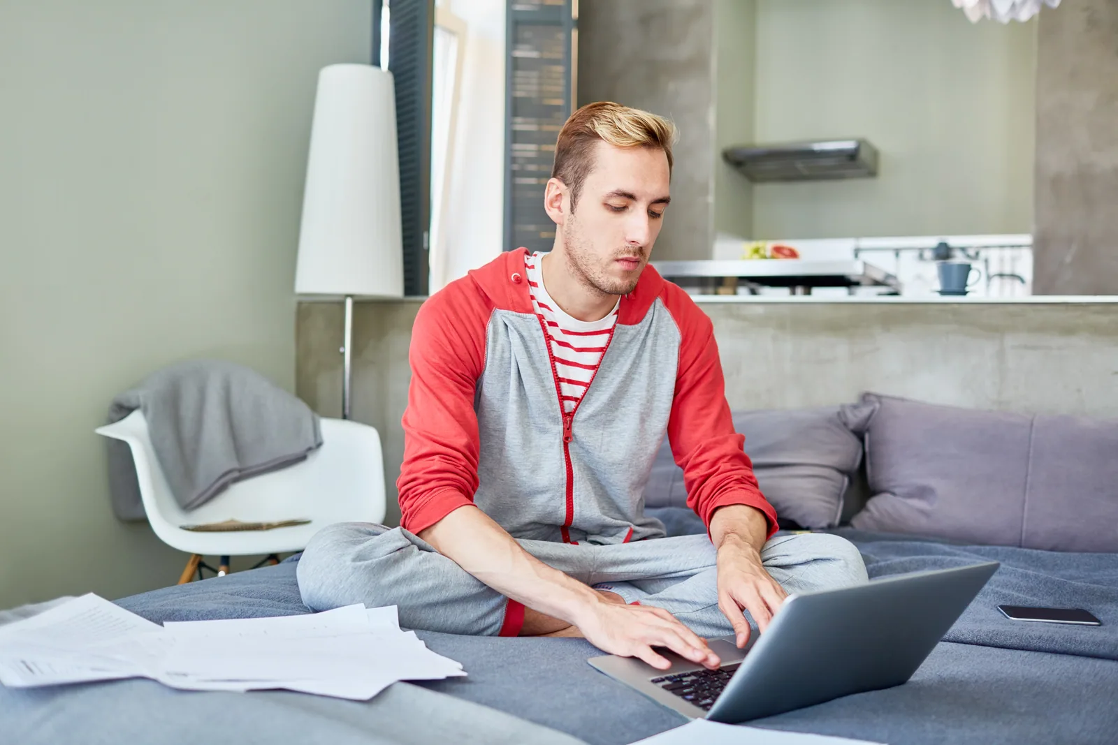 Young man on a sofa checking Sac State GPA requirements on a laptop