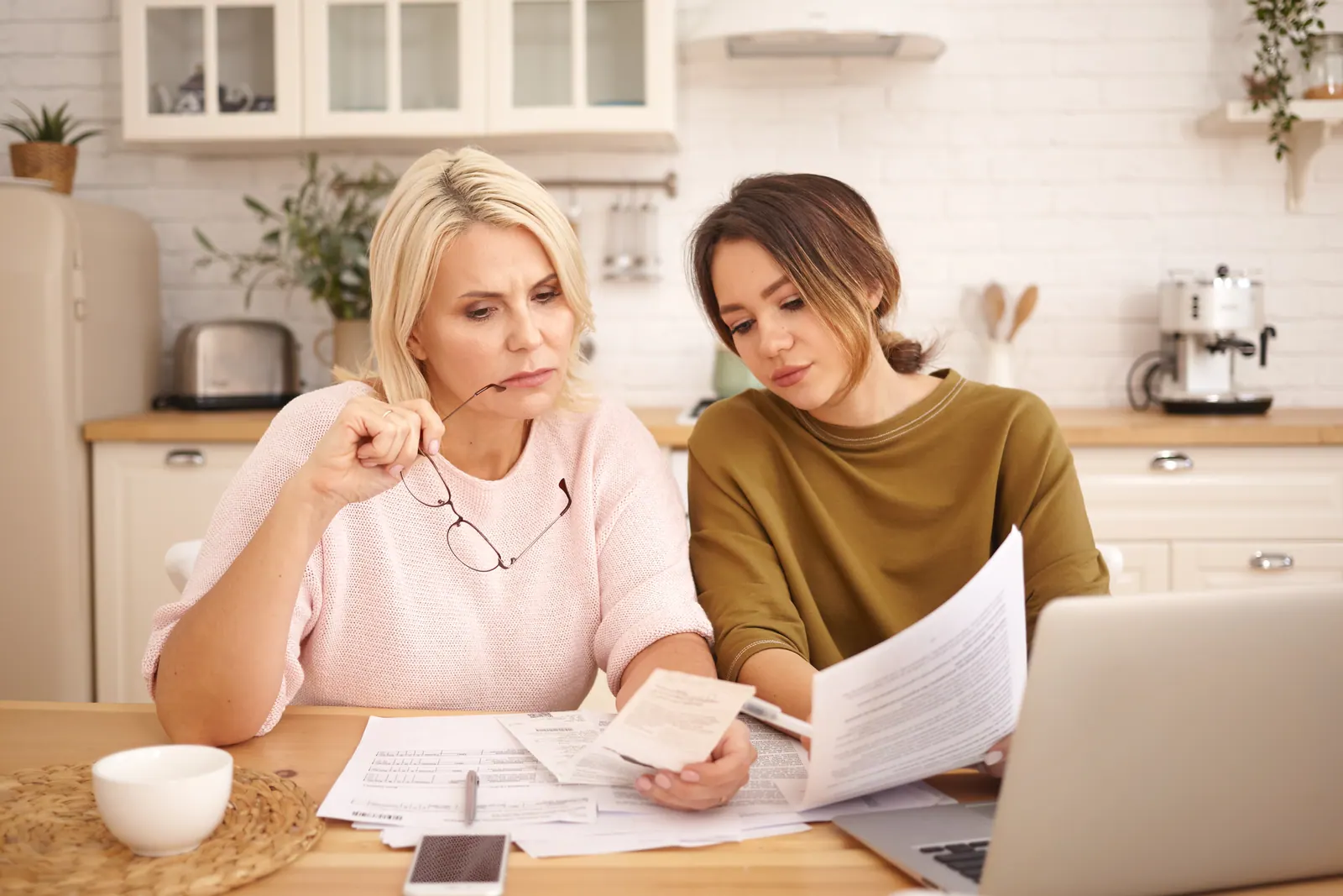 Mother and daughter reviewing private college cost paperwork together at a kitchen table
