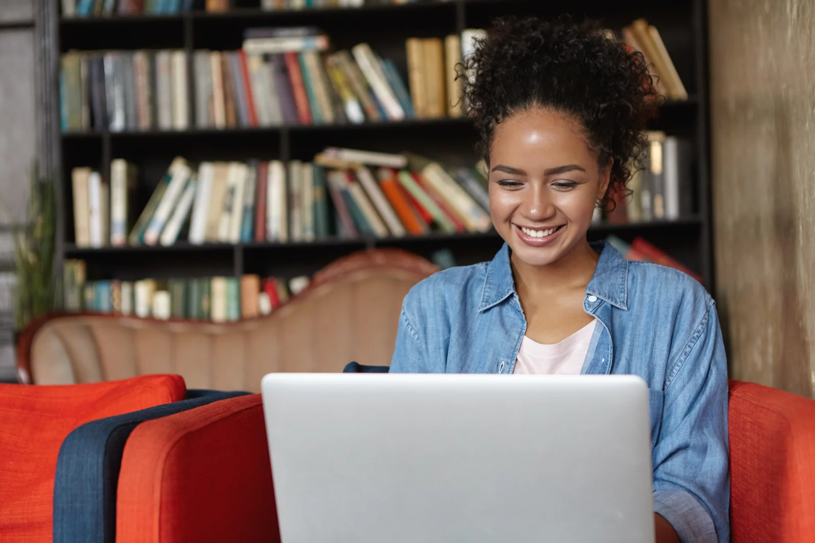 Student smiling at a laptop in a library while completing a Cal State Apply application