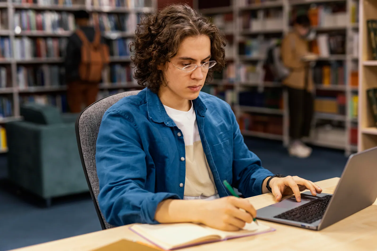 Student working on a laptop in a university library on a Pitzer College application