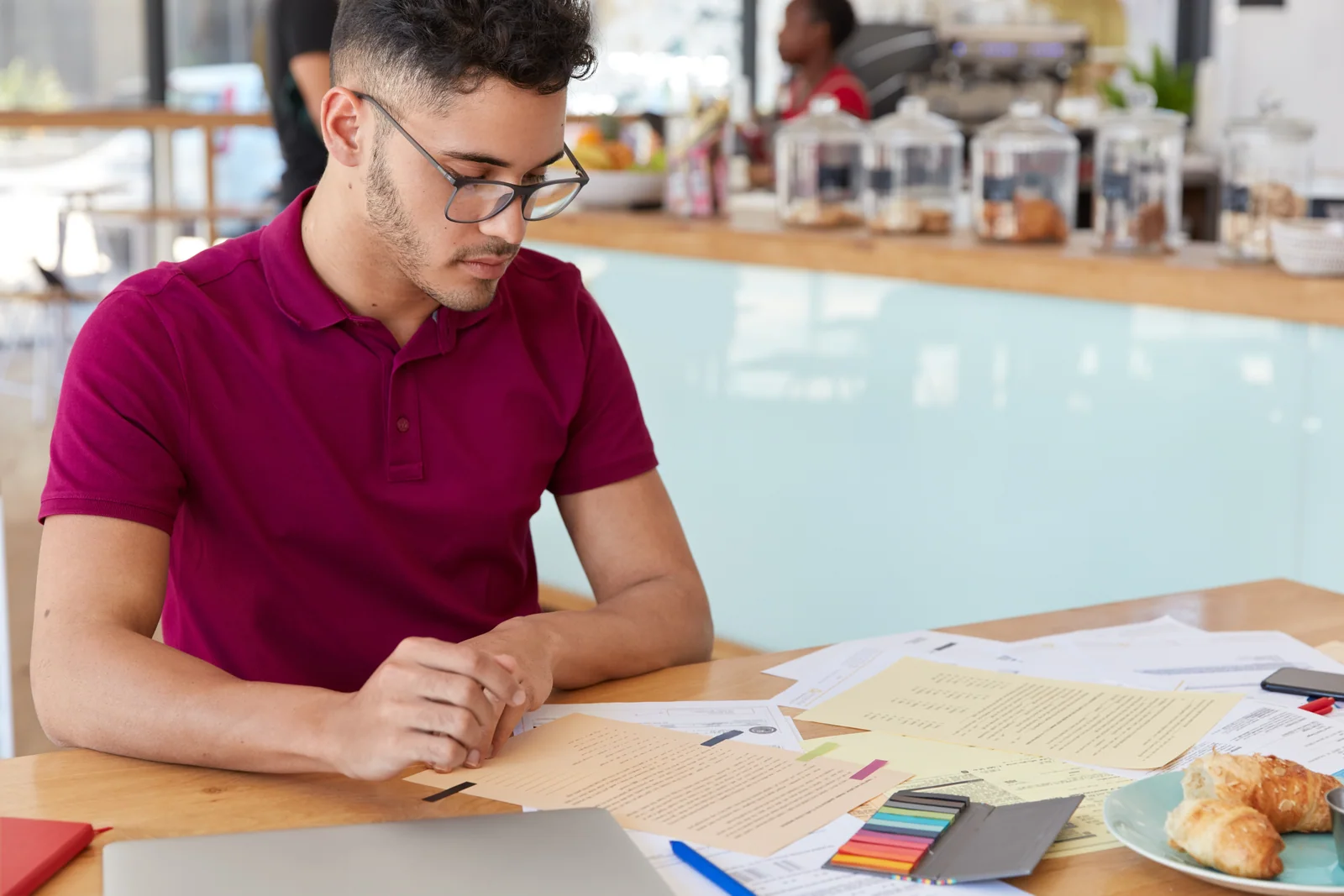 Student reading printed notes with a pen at a cafe table