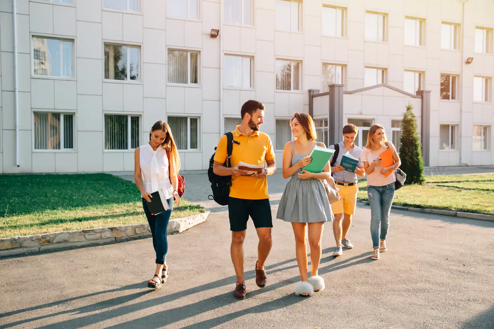Group of college students carrying books while walking across a campus